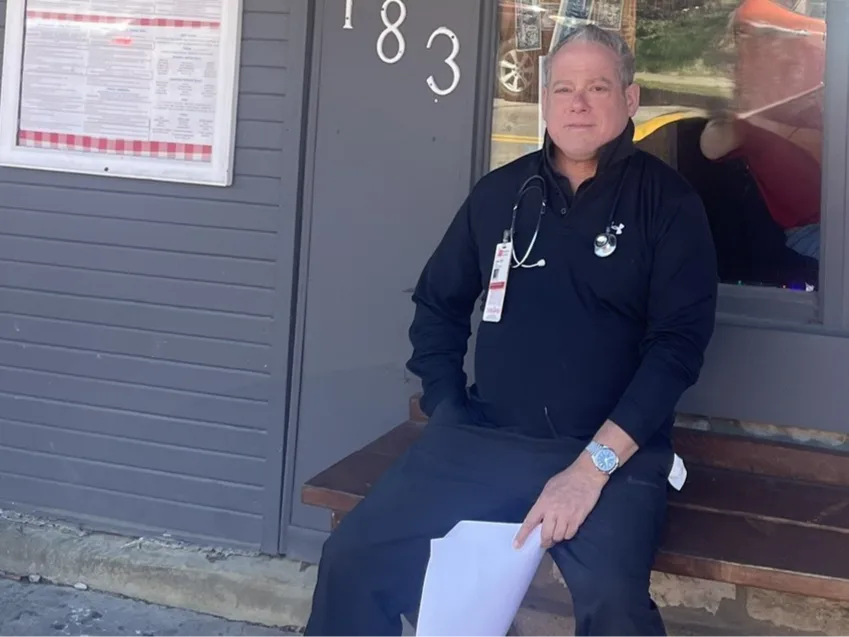 Dr Leve seated on a bench outside the clinic on South High Street.
