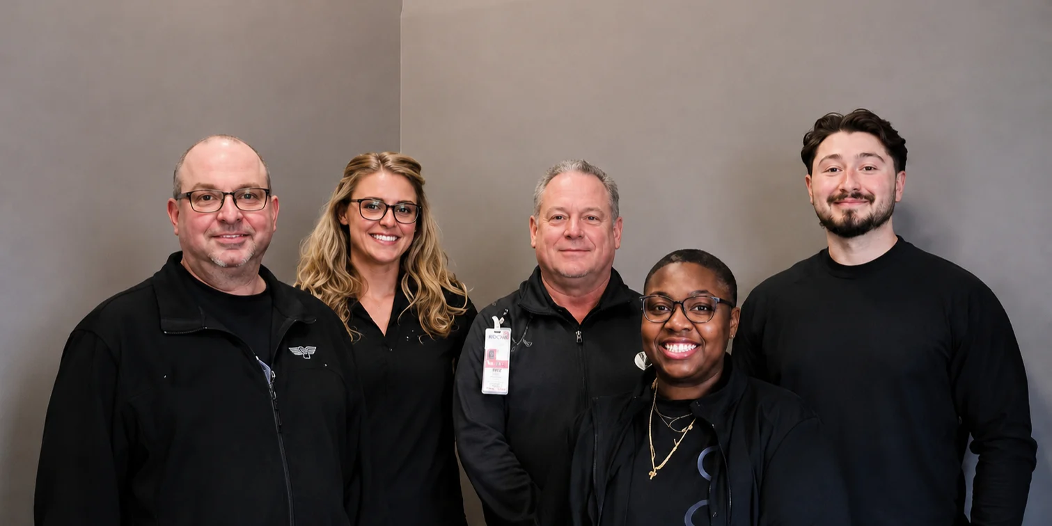 The five-person German Village Men's Clinic team, standing together in black against a grey wall.